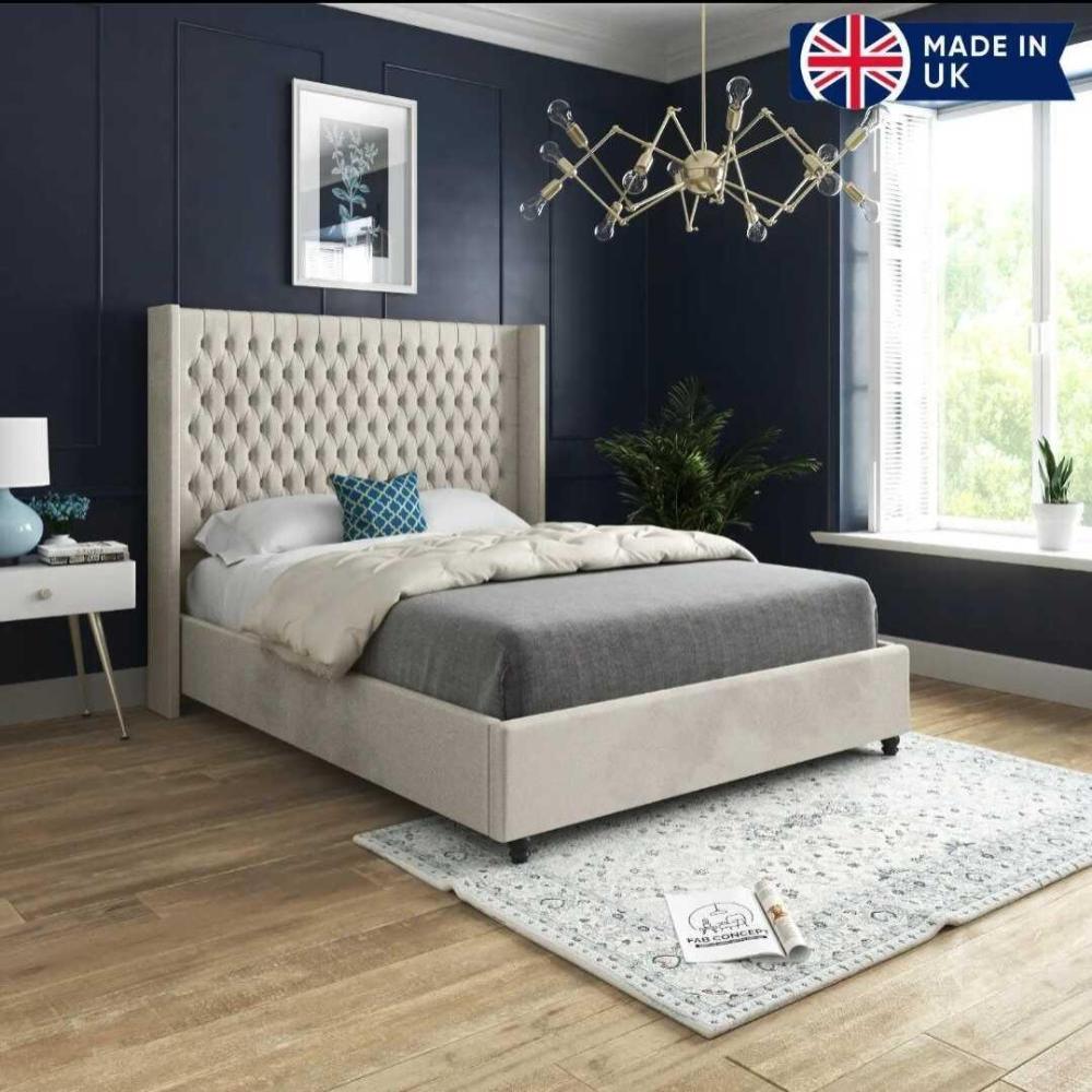 Bedroom with beige upholstered bed and mattress set, blue accent wall, and chandelier.