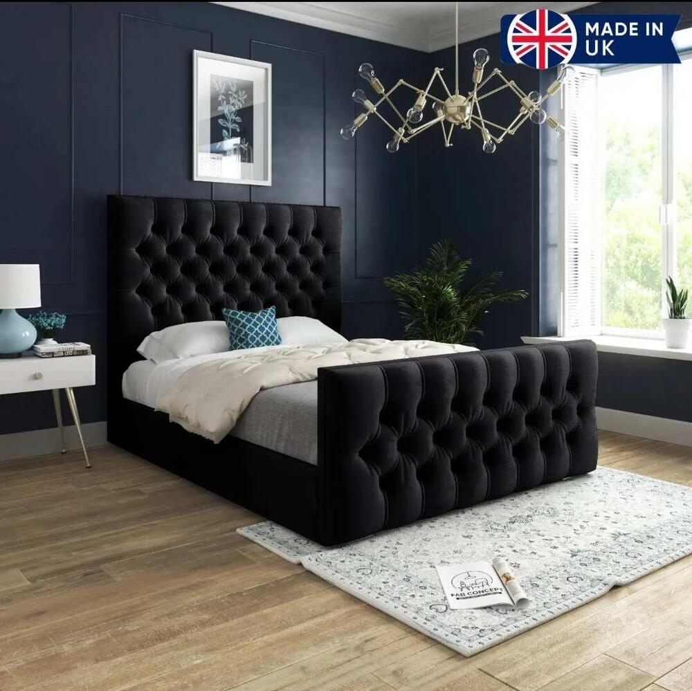 Modern bedroom with a black tufted Chesterfield bed and geometric chandelier, featuring dark blue walls and light wood floors.