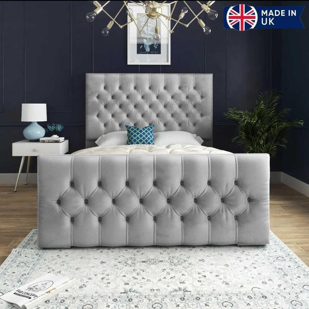 Grey single bed with a tufted headboard, dark blue wall, and geometric chandelier.