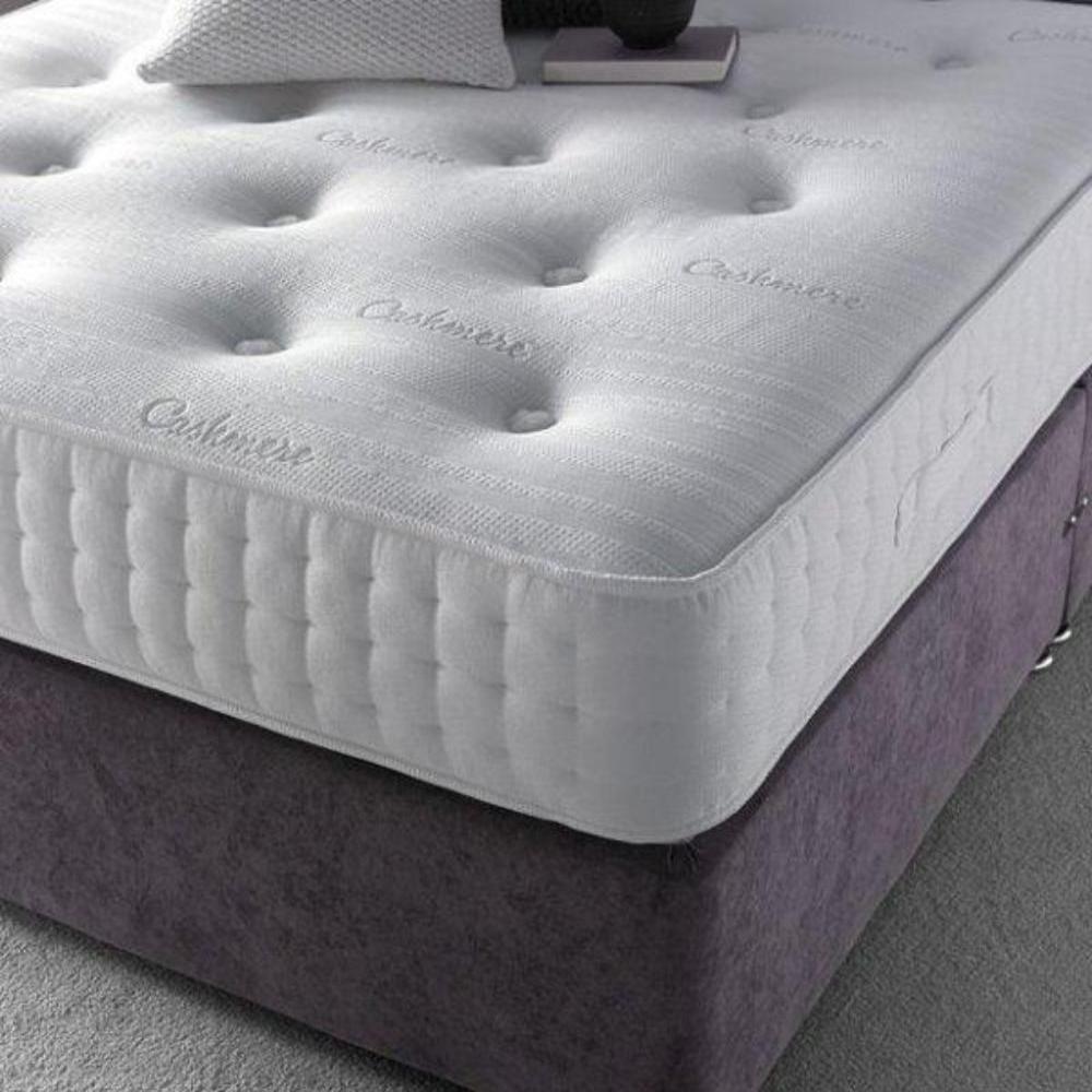 Close-up of a single bed mattress with tufted white surface and "Cashmere" embroidered text.