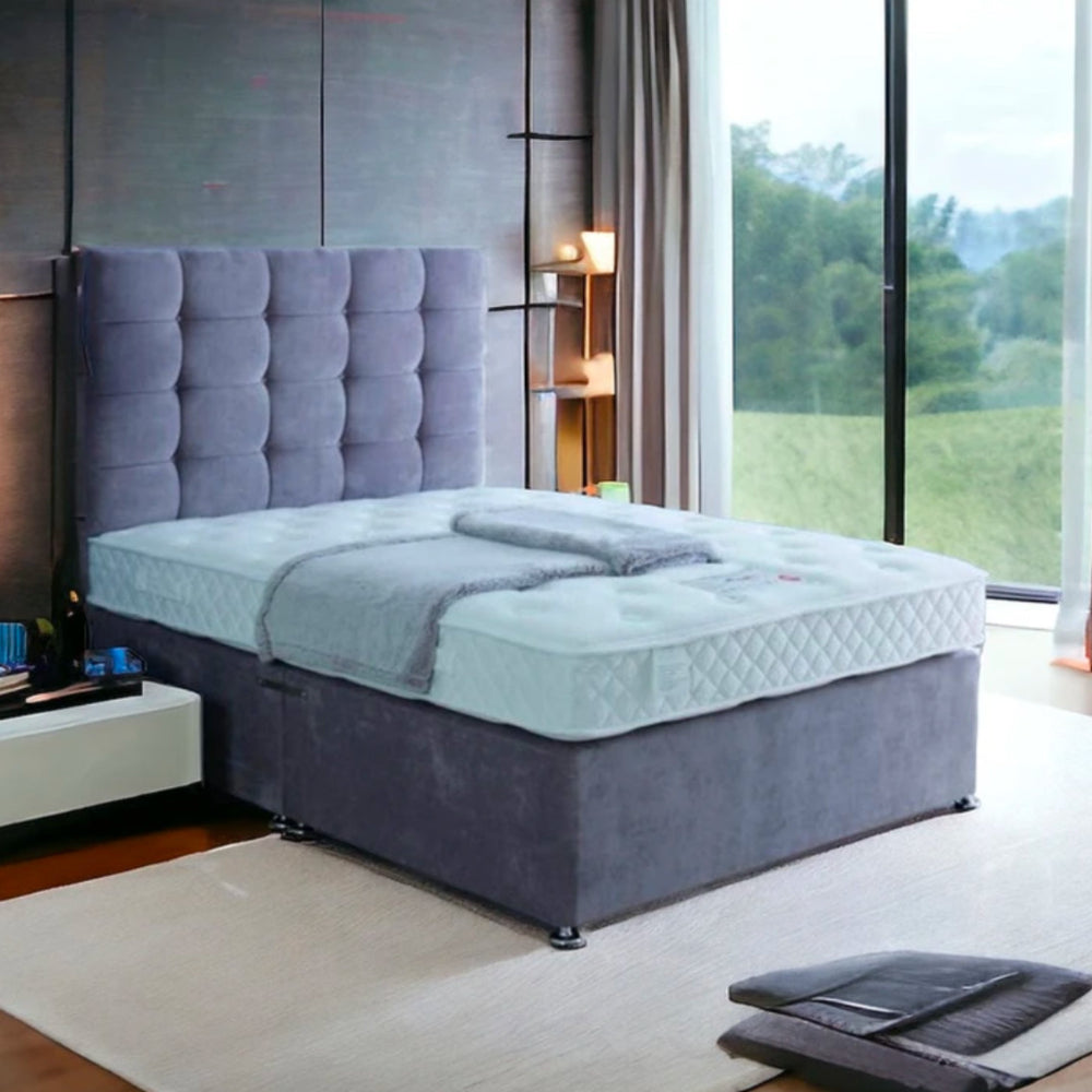 A modern bedroom with a grayish-blue bed and tufted headboard, labeled Excellence 1000.