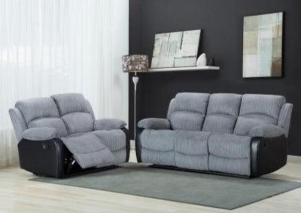 A modern living room with a two-seater sofa and a mid-grey fabric recliner, footrest extended. Light gray cushions contrast with black leather sides. Abstract art decorates a dark accent wall, while sheer white curtains add brightness. Light wooden flooring complements the neutral tones.